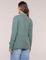 Sobrecamisa beige de lino liviano, con cuello camisero, cierre frontal de botones carey y bolsillos en el pecho. Cuenta con cordón ajustable en la cintura y mangas largas.