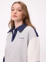 Sweater estilo rugby de Rusty, con diseño color block en tonos bordó, azul marino y verde. Presenta cuello polo en color crema con cierre frontal de botones, mangas largas con puños elásticos y logo de la marca bordado en el pecho.