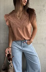 Musculosa de algodón color terracota, con escote en V y cuello ribeteado con bordados en relieve. Presenta mangas cortas con volados sutiles y diseño recto.