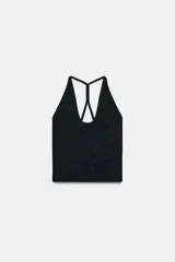 Top corto negro con textura brillante, escote pronunciado en V y tirantes finos que se cruzan en la espalda en diseño tipo nadador.