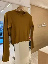 Remera de morley color mostaza, de manga larga, con cuello alto fruncido y terminaciones fruncidas en las mangas.