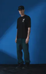 Remera de manga corta y cuello redondo con calce oversize. Presenta una estampa frontal en color crema con diseño artístico de un ángel y una rosa, acompañada de frases en español. Confeccionada en algodón premium.