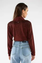 Remera de manga larga con cuello polera, confeccionada en tejido brillante con acabado metalizado en color bordó. Presenta un ajuste regular.