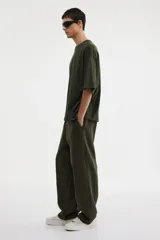 Remera de algodón pesado color verde oscuro, con cuello redondo ribeteado, hombros caídos y corte oversized.