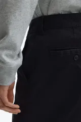 Pantalón de sarga de algodón con corte relajado, cierre de botón y cremallera, bolsillos laterales al bies y bolsillos traseros con botón.