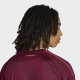 Camiseta de fútbol Adidas de la selección de Venezuela, modelo Primera Equipación 26. Color principal granate con detalles en amarillo dorado en cuello y hombros. Presenta un estampado integral sutil con textura.