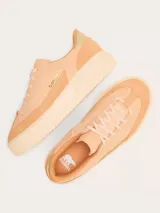 Zapatillas Sorel modelo Ona Ave T Toe, confeccionadas en cuero y gamuza en tonos salmón y tostado, con suela plataforma ranurada y detalle metalizado en el talón.