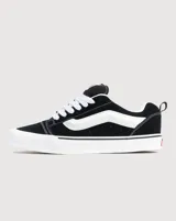 Championes Vans modelo Knu Skool, de diseño inspirado en los años 90 con silueta voluminosa. Confeccionados en gamuza negra, presentan lengüeta y cuello acolchados, Sidestripe en relieve 3D, tiradores en el talón y suela de goma con diseño waffle.