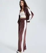Pantalón wide leg de textura aterciopelada color bordó, con cintura elástica ajustable mediante lazo y franjas laterales en contraste.