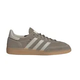 Championes adidas Handball Spezial inspirados en el modelo de 1979, confeccionados en gamuza gris topo con las clásicas tres tiras y refuerzo de talón en tono claro, inscripción lateral en letras doradas y suela de goma de tipo caramelo.