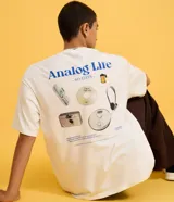 Remera oversized de algodón color blanco crudo, con cuello redondo, manga corta y estampa trasera con la leyenda "Analog Life" y gráficos de tecnología retro en tonos azules y grises.
