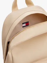 Mochila Tommy Jeans de diseño redondeado en color beige con base negra. Cuenta con compartimento principal con cierre de cremallera, bolsillo frontal con cierre, correas ajustables acolchadas y asa superior. Incluye parche distintivo de la marca en la parte frontal.