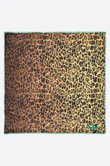 Chal cuadrado con estampado animal print y efecto degradado de marrón a amarillo. Presenta bordes con flecos cortos en color verde contraste y etiqueta de la marca en una esquina.