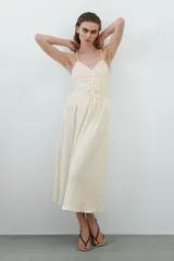 Vestido midi de color blanco con textura arrugada, escote en V, breteles finos y detalle drapeado en el busto.