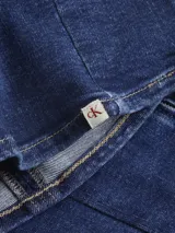 Vestido corto de denim azul oscuro, sin mangas y con ajuste bodycon. Presenta costura vertical central en el frente y cierre metálico en la espalda.