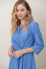 Vestido midi cruzado de seda con estampado de rayas celestes y blancas, escote en V con solapa, mangas tres cuartos y detalle de nudo drapeado en la cintura.