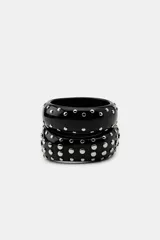Pack de dos pulseras tipo brazalete fabricadas en resina de color negro, decoradas con tachas metálicas circulares en color plateado de diferentes tamaños.