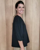 Remera blanca con cuello en V, cuerpo de algodón y mangas abullonadas de encaje bordado con puños elásticos.