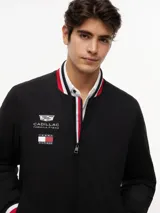 Campera estilo bomber de Tommy Hilfiger en colaboración con Cadillac Formula 1® Team, color negro. Cuenta con cuello tipo béisbol, cierre frontal de cremallera y ribetes tejidos a rayas rojas, blancas y azules en el cuello, puños y dobladillo. Presenta parches bordados del equipo en el pecho.