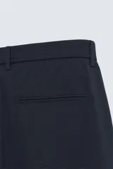 Pantalón de corte slim fit confeccionado en tejido elástico, con cintura elástica, cierre frontal con cremallera y botón, bolsillos laterales y bolsillos traseros de vivo.