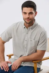 Camisa de manga corta confeccionada en mezcla de lino y algodón, con estampado de cuadros pequeños en tonos azules. Presenta cuello camisero con botones, cierre frontal abotonado, bolsillo aplicado en el pecho y dobladillo redondeado.