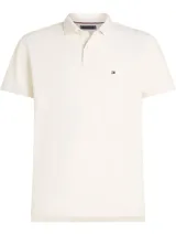 Chomba blanca de Tommy Hilfiger, modelo 1985, de corte regular, con cuello tipo chomba, cartera de dos botones, mangas cortas y logo bordado en el pecho.