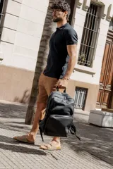 Mochila urbana de diseño minimalista en color negro, confeccionada en poliuretano. Cuenta con un compartimento principal amplio, un bolsillo frontal grande con cierre y un diseño ergonómico con correas ajustables.