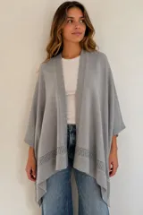 Ruana gris de tejido de algodón, con diseño abierto y detalle de franja calada en el borde inferior.