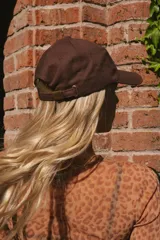 Gorra marrón de algodón con logo bordado en celeste en el frente y ganchito ajustable en la parte trasera.