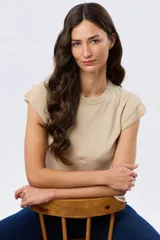 Remera tejida de algodón en color beige, de cuello redondo, sin mangas y con detalles de volados estructurados en los hombros.