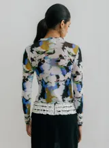 Top de manga larga, ajustado al cuerpo, confeccionado en microtul transparente con estampado floral en tonos marrones sobre fondo azul celeste. Presenta cuello redondo.