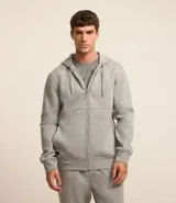 Saco deportivo gris de algodón y poliéster, con capucha ajustable con cordón, cierre frontal con cremallera, mangas largas con puños ajustados y bolsillos laterales.