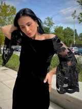 Blusa negra de terciopelo con escote bote y mangas largas acampanadas de encaje con detalles de lentejuelas.