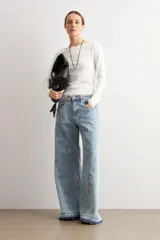 Jean wide leg de tiro medio con diseño bicolor en tonos celestes y costuras decorativas verticales. Presenta botamanga ancha con dobladillo deshilachado y lavado diferenciado.