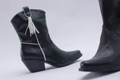 Botas estilo texanas de caña media, confeccionadas en cuero con estampado animal print tipo vaca en blanco y negro. Presentan un diseño de punta fina y taco cuadrado.