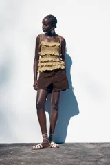 Shorts de jean color marrón oscuro, de tiro medio y corte mom fit. Con cinco bolsillos, cierre frontal con cremallera y botón.