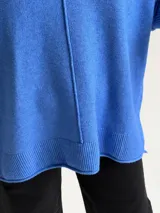 Sweater de tejido de punto color azul, con escote en V, manga larga con puños acanalados y diseño holgado con costura central vertical y ruedo asimétrico.