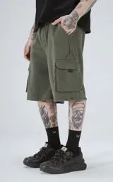 Bermuda de algodón rústico color verde militar, de calce oversize, con cintura elástica y bolsillos cargo con cierre en los laterales.