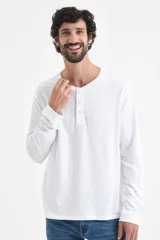 Remera manga larga de algodón en color blanco, con cuello redondo y tapeta frontal con tres botones.