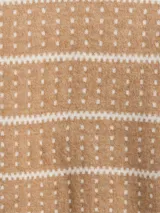 Buzo de punto con cuello alto, diseño estampado estilo fairisle con rayas horizontales y puntos en tonos tostado y blanco. Presenta mangas largas con puños acanalados y ruedo recto.