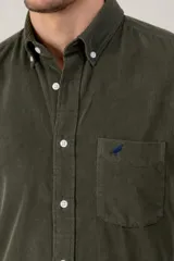 Camisa de pana verde oscuro de corte clásico, con cuello button-down, cierre frontal de botones, bolsillo en el pecho con detalle bordado y mangas largas.