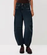 Pantalón de jean estilo baggy balloon, de tiro medio y corte amplio con diseño redondeado en las piernas. Presenta recortes laterales, cierre frontal con botón y cremallera, y bolsillos funcionales.