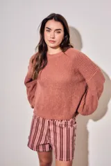 Sweater de tejido bouclé texturado color beige, con cuello redondo y mangas largas holgadas de corte amplio.