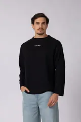 Buzo de cuello redondo y manga larga, confeccionado en tejido de punto acanalado de color negro. Presenta un diseño minimalista con un pequeño logo estampado en el pecho y un corte relajado.