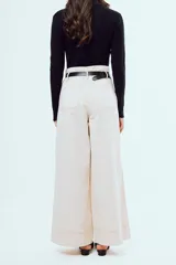 Pantalón marrón de corte ancho y talle alto, con pinzas frontales y bolsillos laterales.