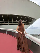 Vestido largo marrón de crepe texturizado, con cuello halter fruncido, diseño holgado y falda larga con vuelo.