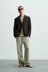 Blazer regular fit color marrón oscuro confeccionado en tejido de lino. Tiene cuello con solapas de muesca, manga larga con puño abotonado, bolsillo de vivo en el pecho, bolsillos de solapa en la cadera, bolsillo interior, bajo con aberturas en la espalda y cierre frontal con botonadura.