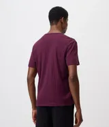 Remera masculina negra de manga corta, con cuello redondo y abertura frontal tipo Henley con botones claros. Presenta un diseño de textura acanalada vertical y corte regular.