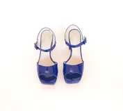 Sandalias de cuero color azul brillante, con taco de 10 cm y plataforma de 2 cm. Presentan tiras anchas en la parte delantera y una tira ajustable con hebilla en el tobillo.