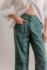 Pantalón de gabardina color crudo con estampado artístico de motivos botánicos y arquitectónicos. Presenta corte recto, tiro medio y bolsillos laterales.